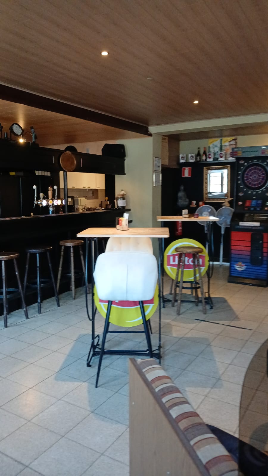 Hoge tafels bij de toog met dartsbord op de achtergrond