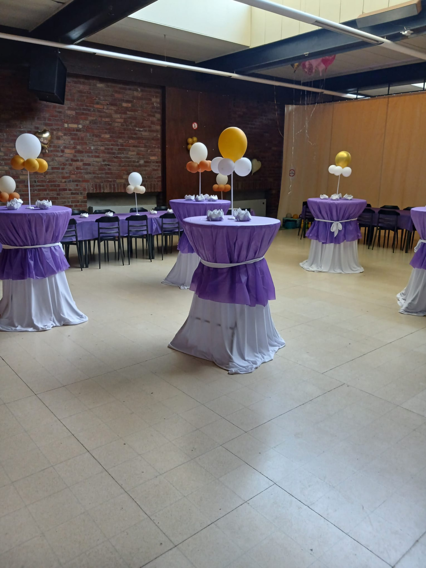 Zaal met paars-witte sta-tafels en ballonnen